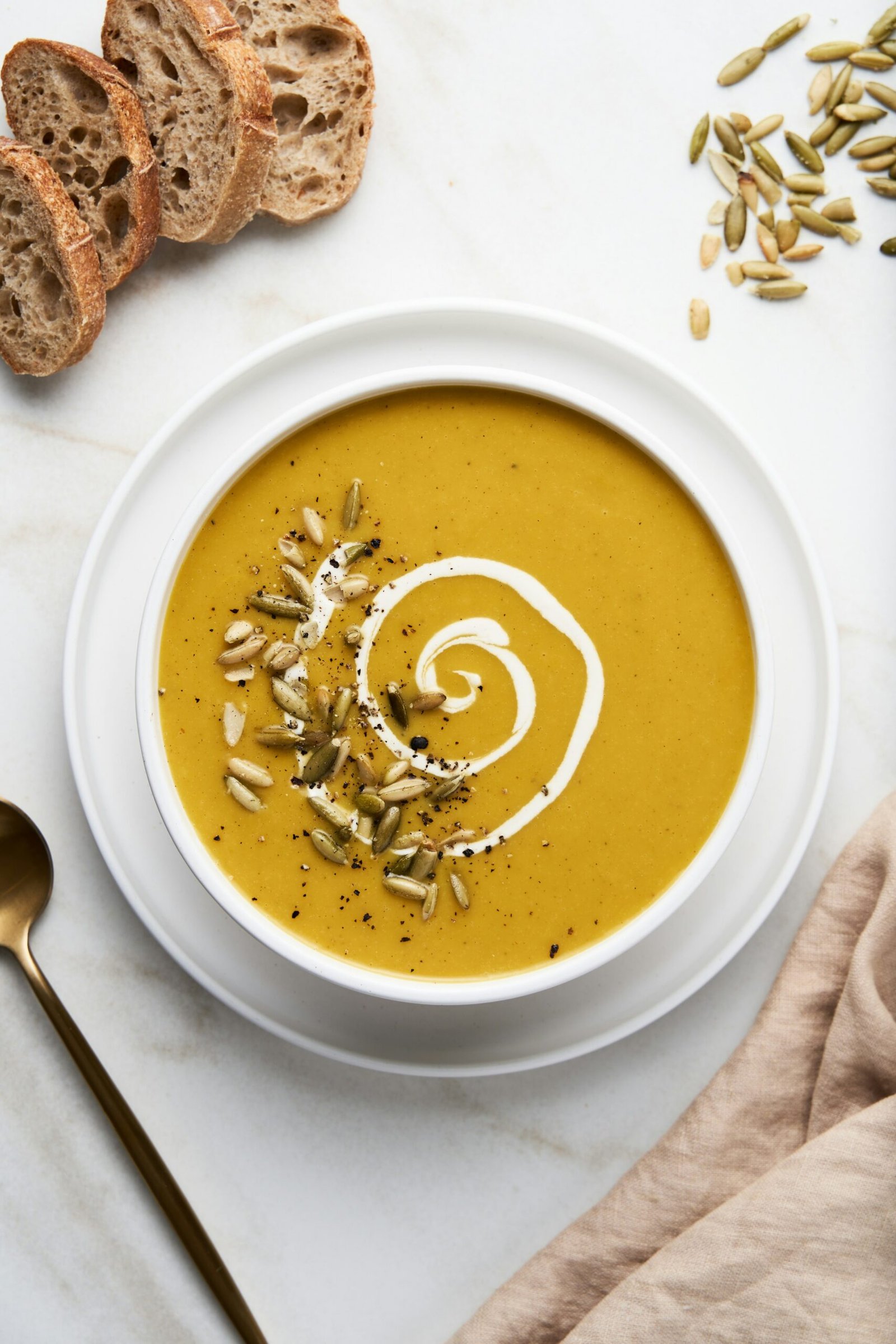 Creamy pumpkin soup in a rustic bowl garnished with seeds and cream